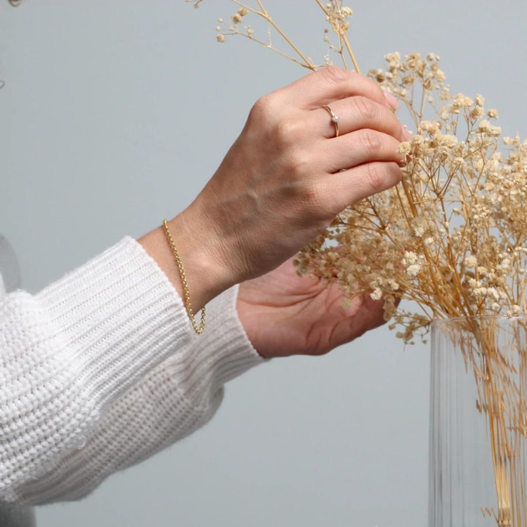 A woman is holding a bunch of dried flowers