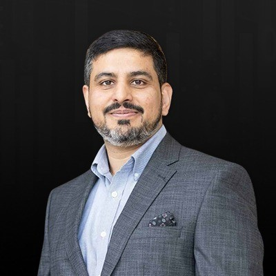 A man in a suit and tie standing in front of a black background