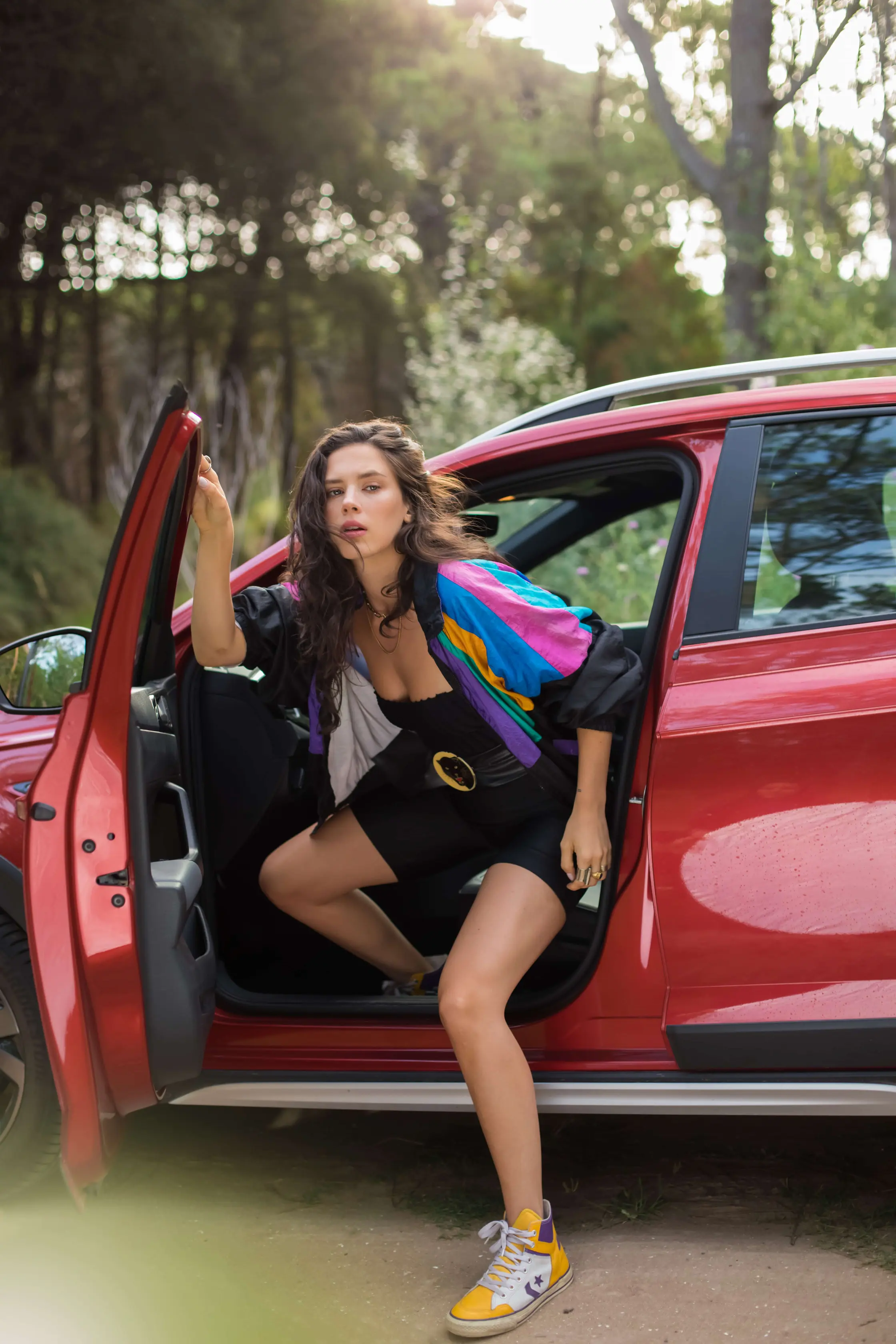 A woman sitting in the open door of a red car