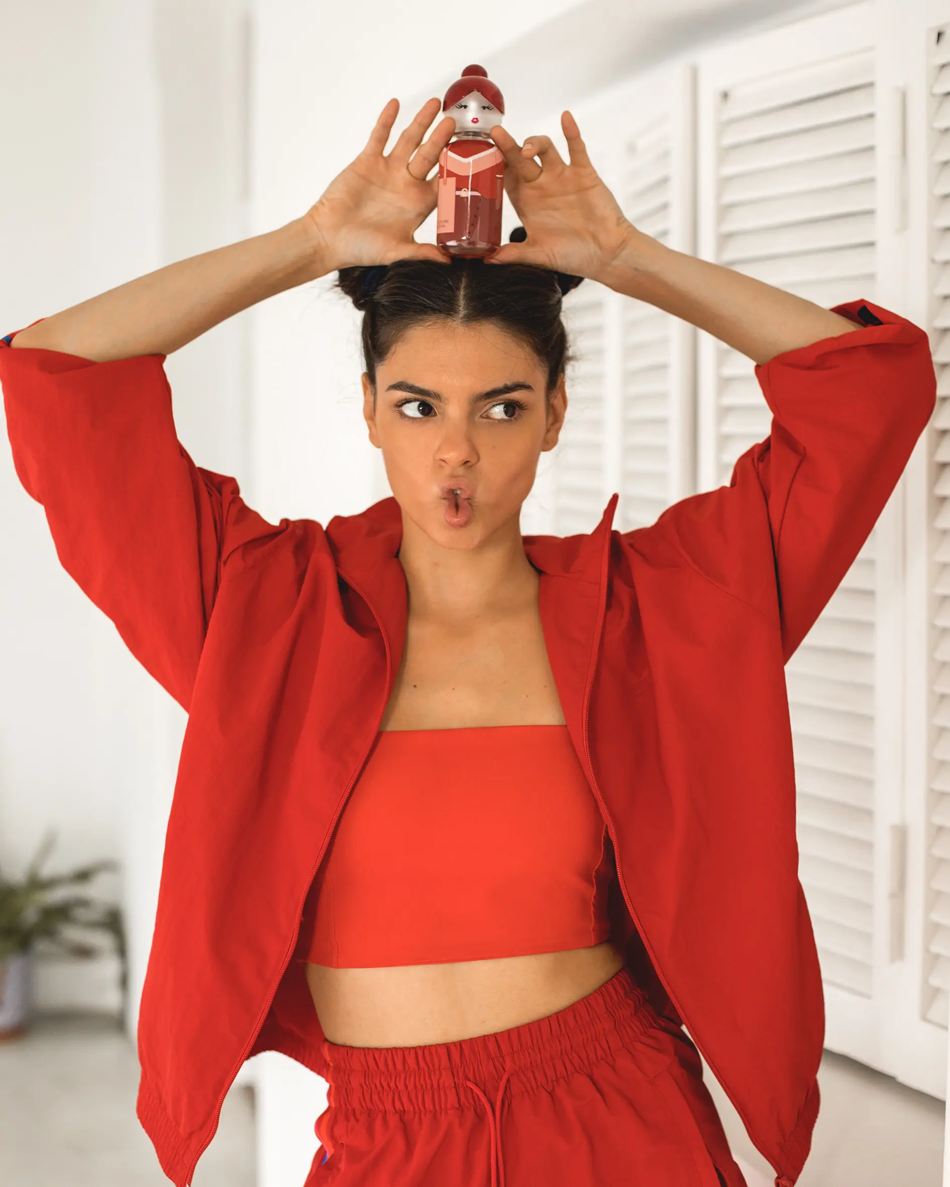 A woman in a red top is holding her hair in the air