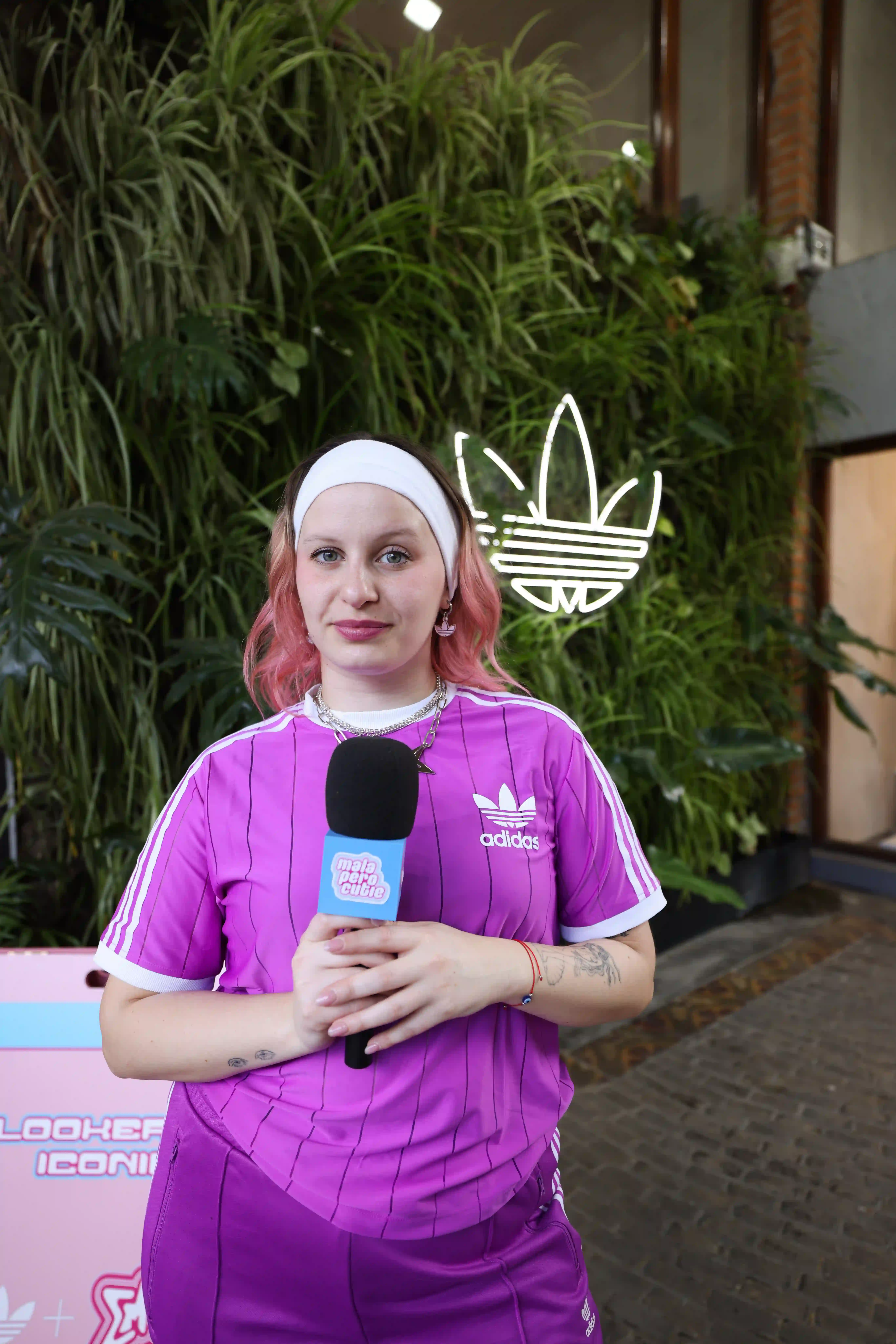 A woman with pink hair is holding a microphone
