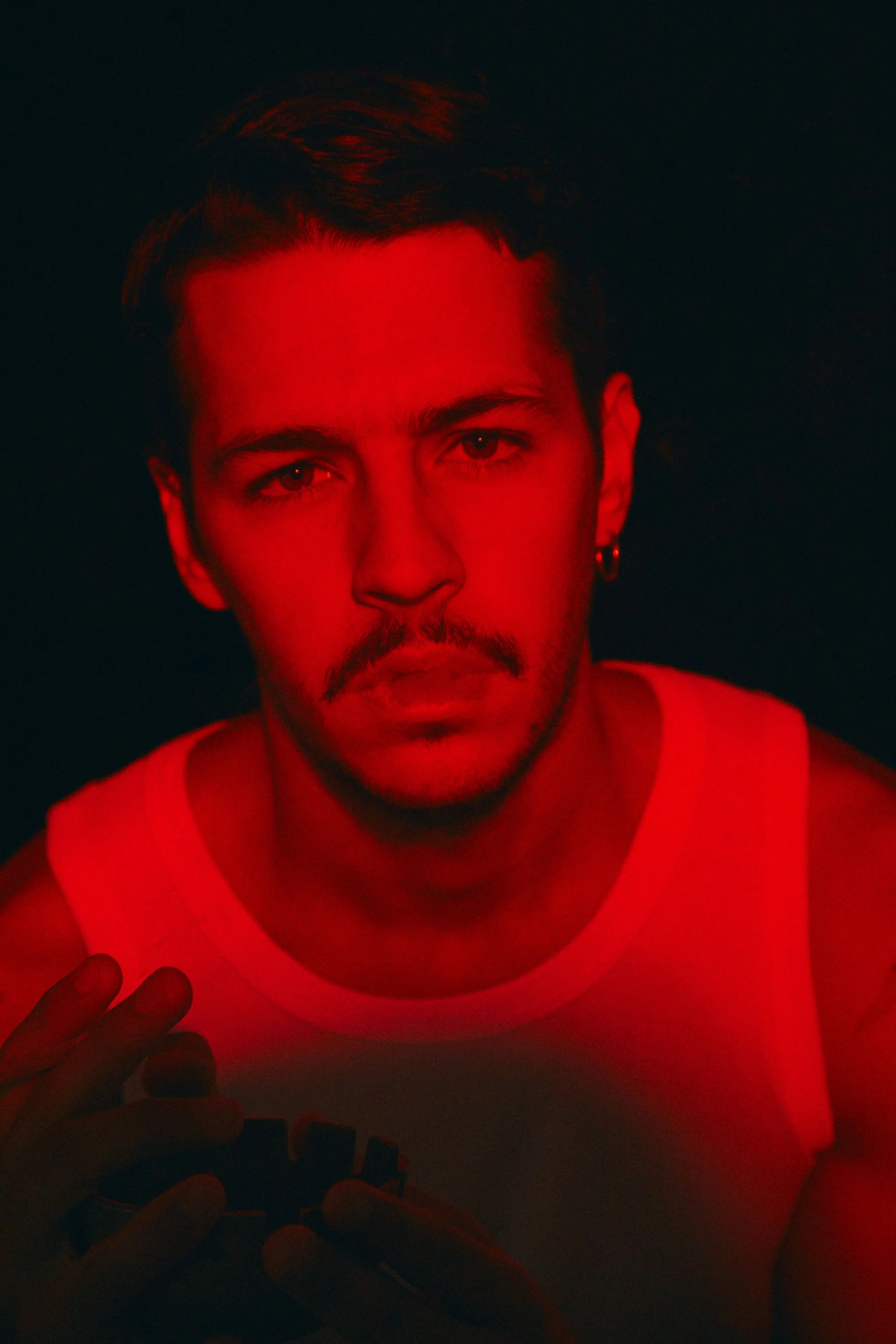 A man in a red tank top holding a cell phone