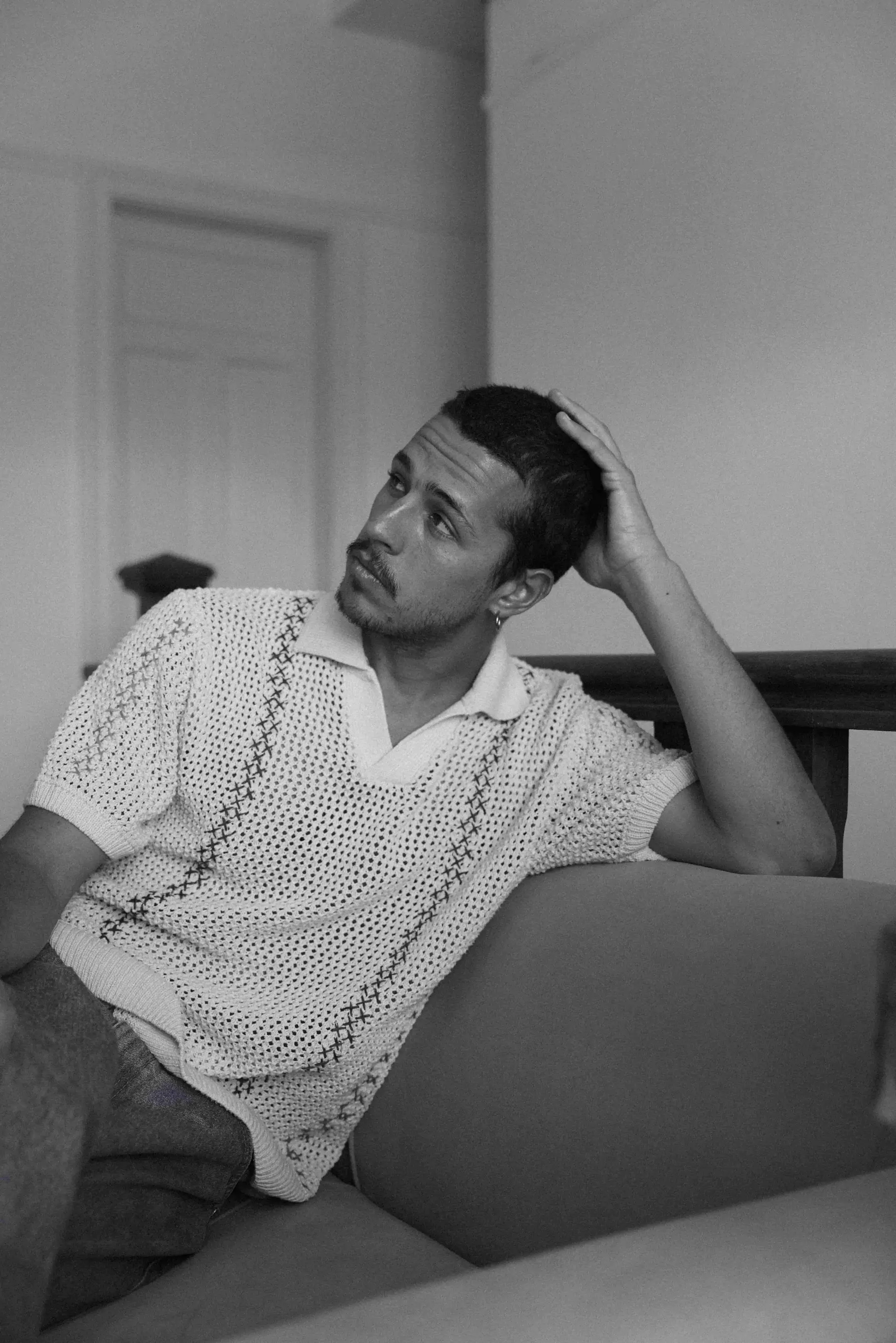 A man sitting on a couch with his hand on his head