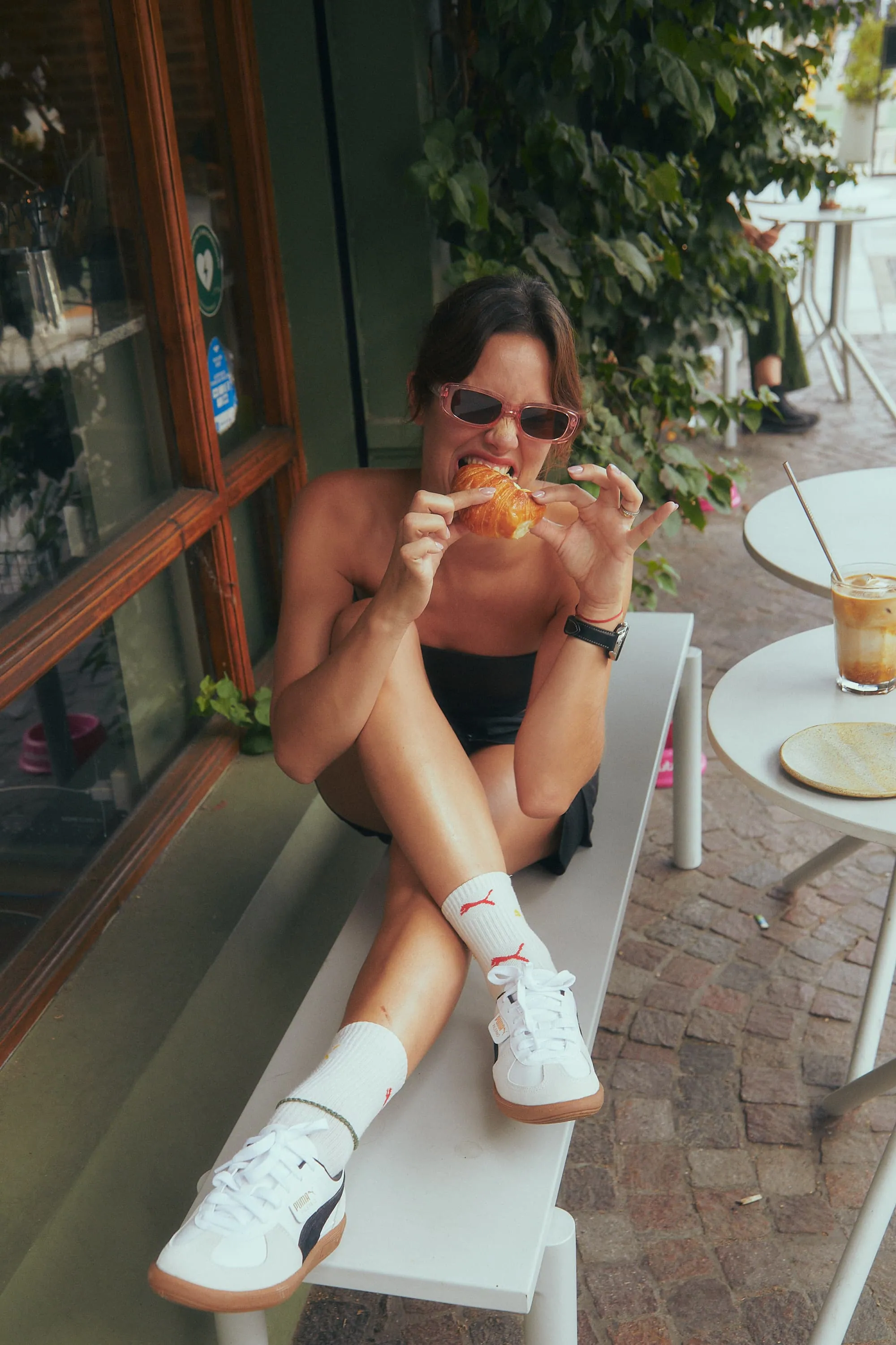 A woman sitting on a bench eating a piece of pizza