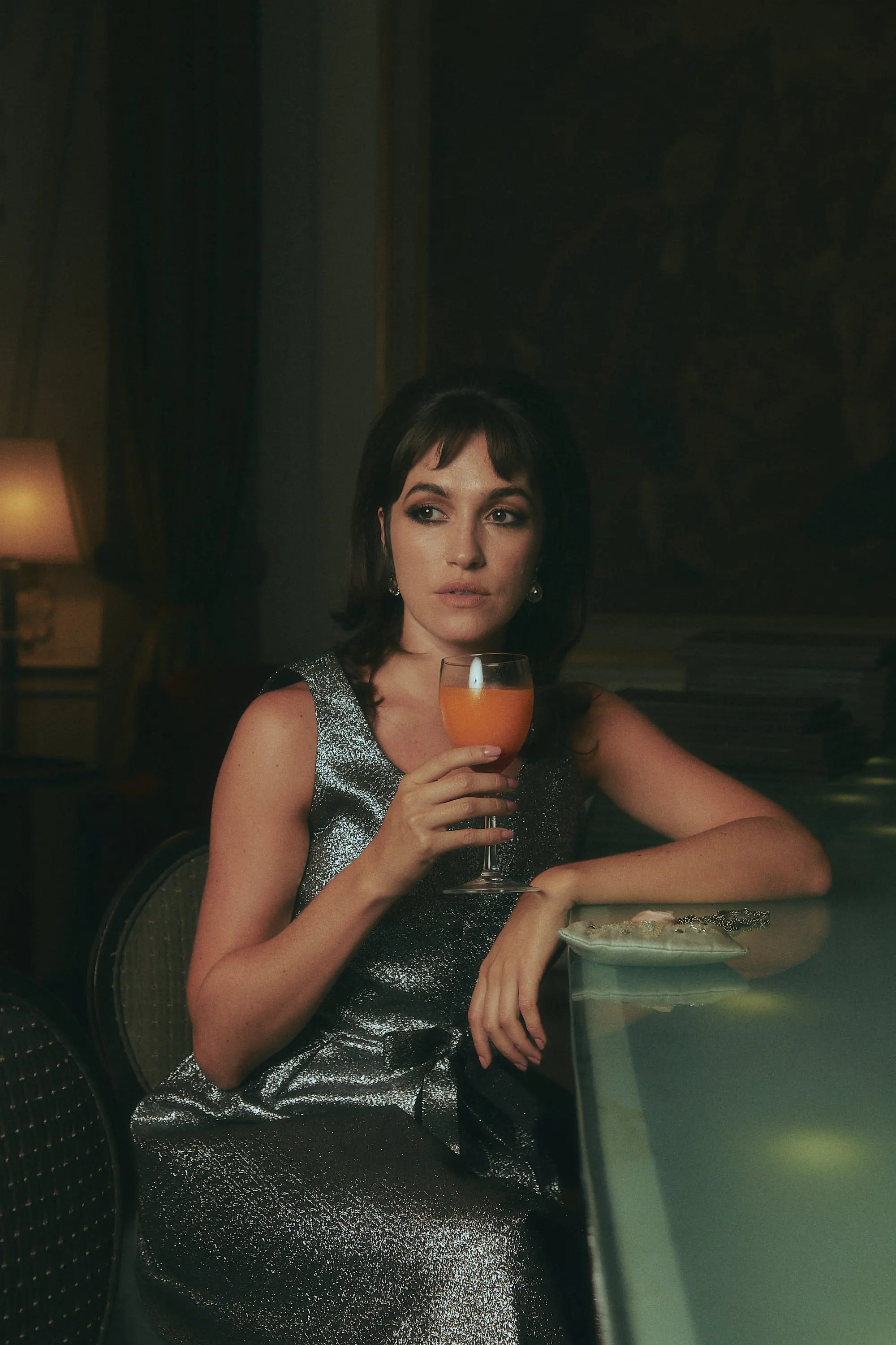 A woman sitting at a table holding a drink