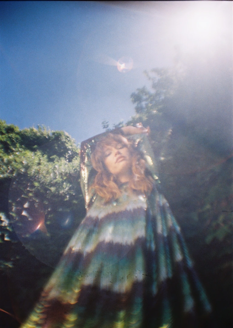 A woman in a colorful dress standing in front of trees