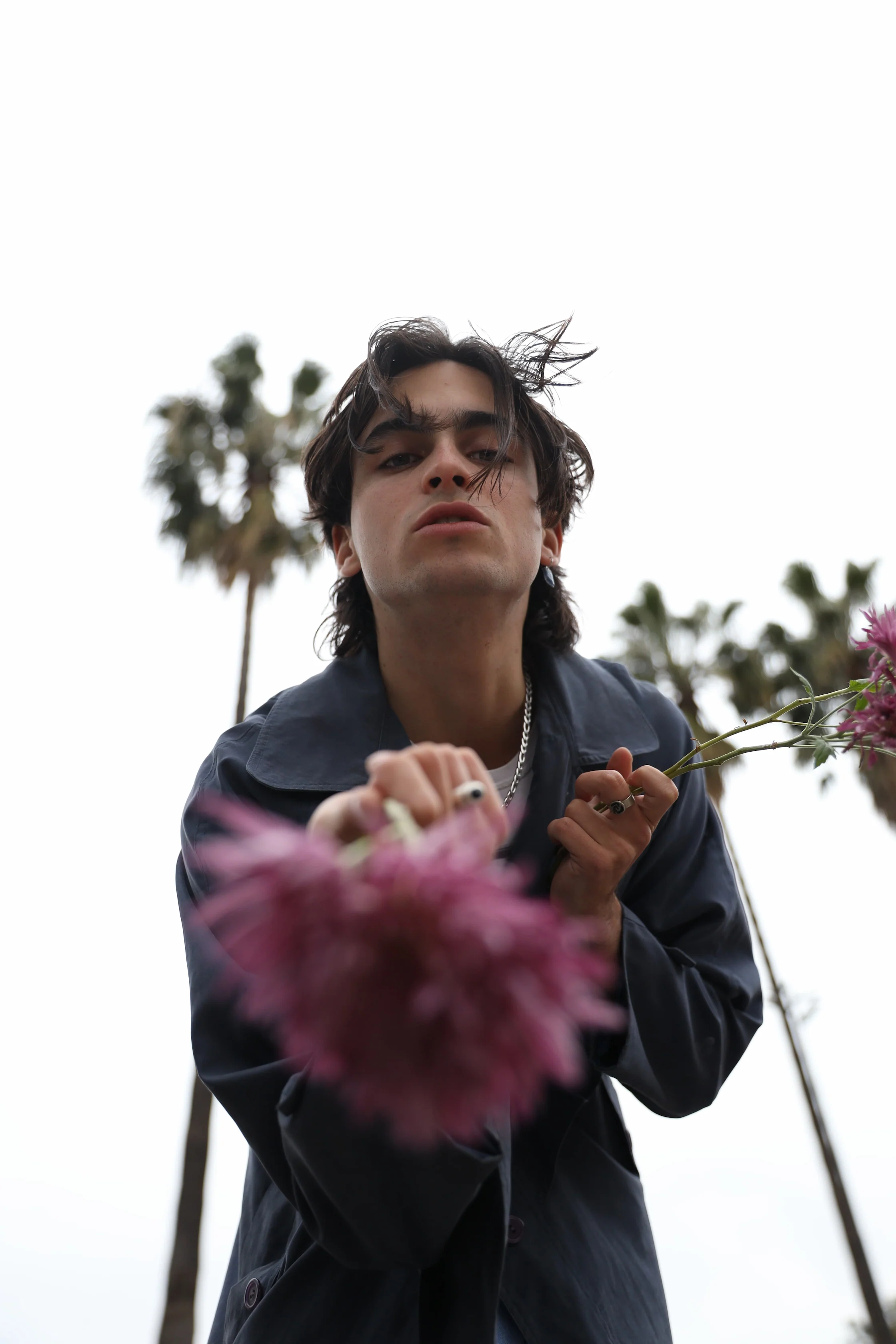A man holding a flower in front of palm trees