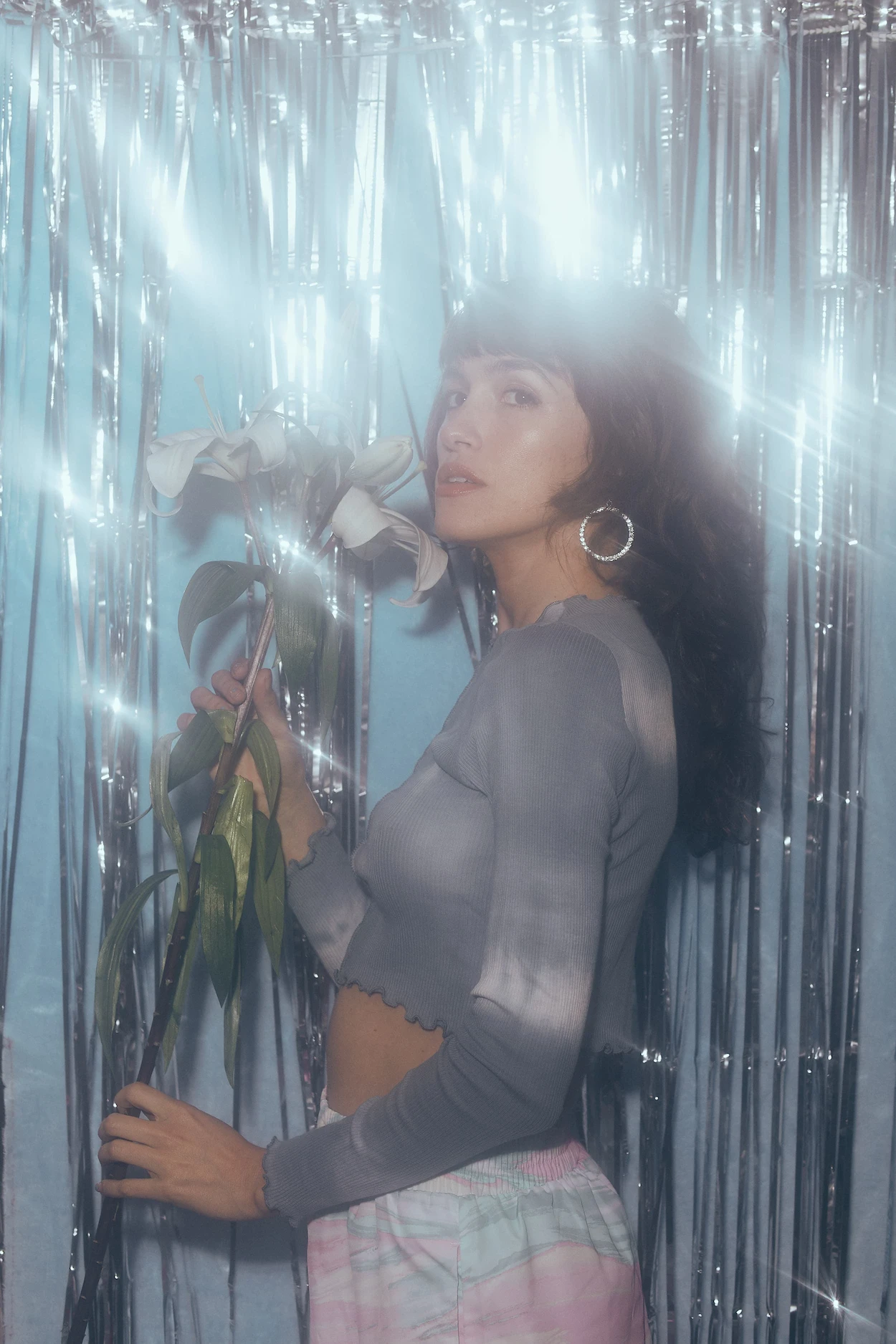 A woman holding a rose in front of a curtain