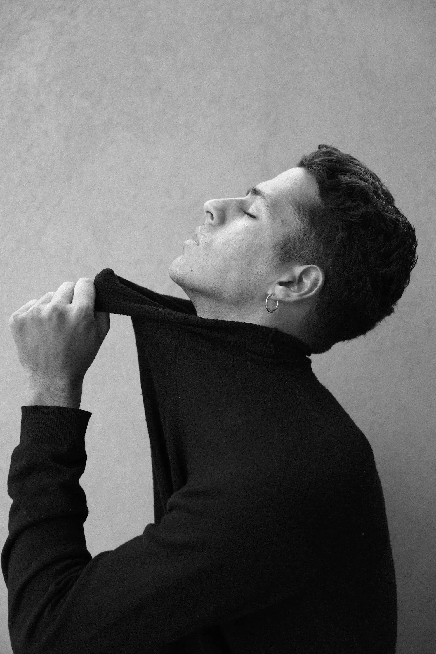 A black and white photo of a man adjusting his tie