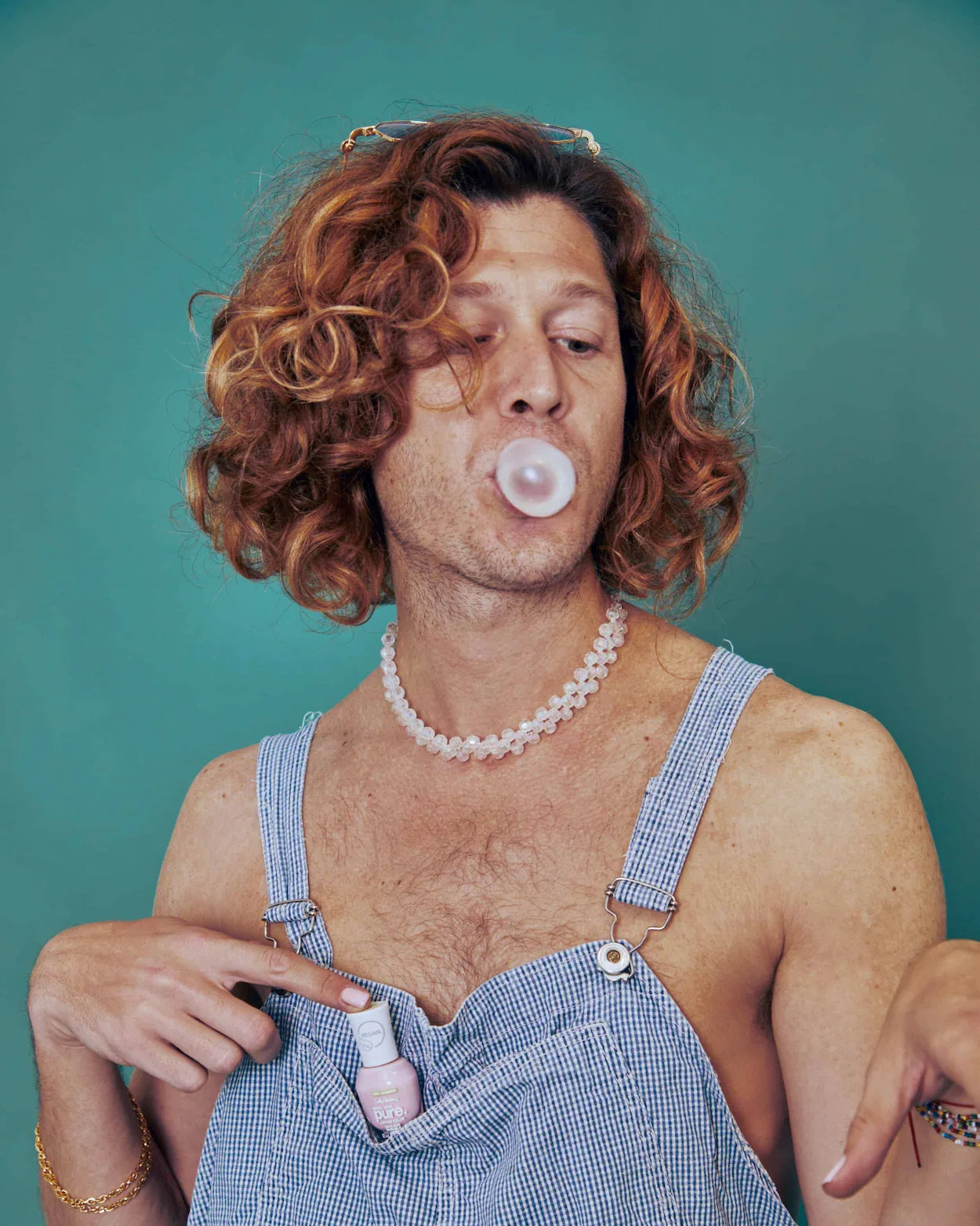 A man blowing a bubble with a pacifier in his mouth