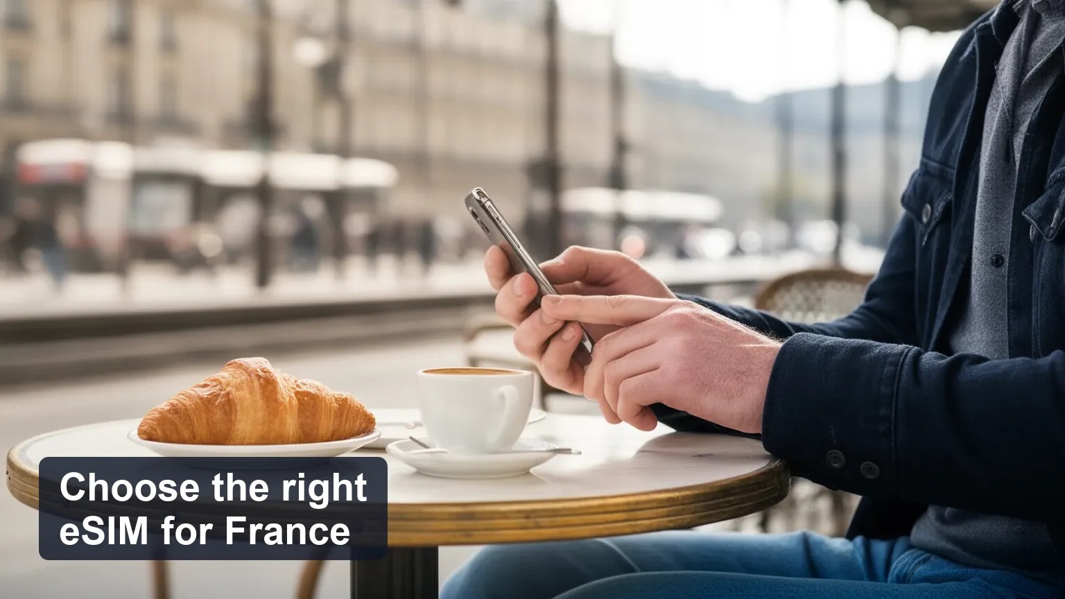 Traveler at a Paris cafe table checking a phone with the screen turned away from the camera, morning light and blurred street background.